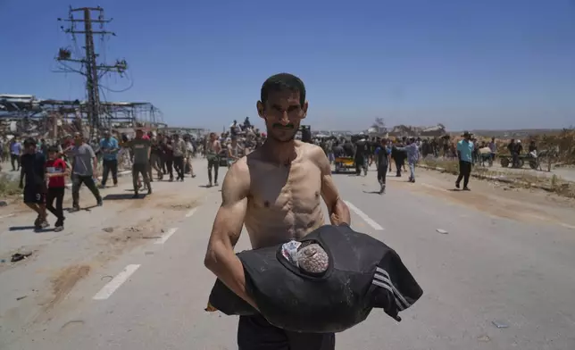 A Palestinian man carries food in his T-shirt after receiving aid from the Gaza Humanitarian Foundation, a U.S.-backed organization approved by Israel, in Khan Younis, southern Gaza Strip, on Thursday, May 29, 2025. (AP Photo/Abdel Kareem Hana)