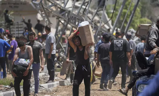 Palestinians carry boxes and bags containing food and humanitarian aid packages delivered by the Gaza Humanitarian Foundation, a U.S.-backed organization approved by Israel, in Khan Younis, southern Gaza Strip, on Thursday, May 29, 2025. (AP Photo/Abdel Kareem Hana)