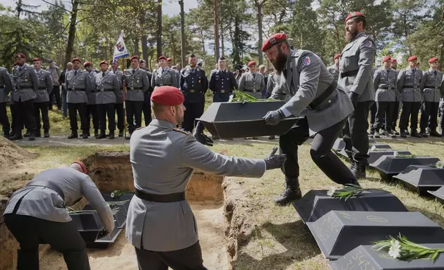 German soldiers carry the small coffins with the remains of fallen German soldiers of WWII to the grave during a funeral service at a memorial site for fallen soldiers in Halbe, Germany, Wednesday, April 30, 2025. (AP Photo/Ebrahim Noroozi)