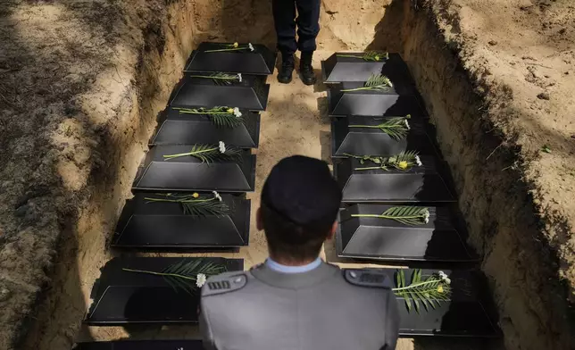 Small coffins with the remains of fallen German soldiers of WWII are placed in the mass grave during a funeral service at a memorial site for fallen soldiers in Halbe, Germany, Wednesday, April 30, 2025. (AP Photo/Ebrahim Noroozi)