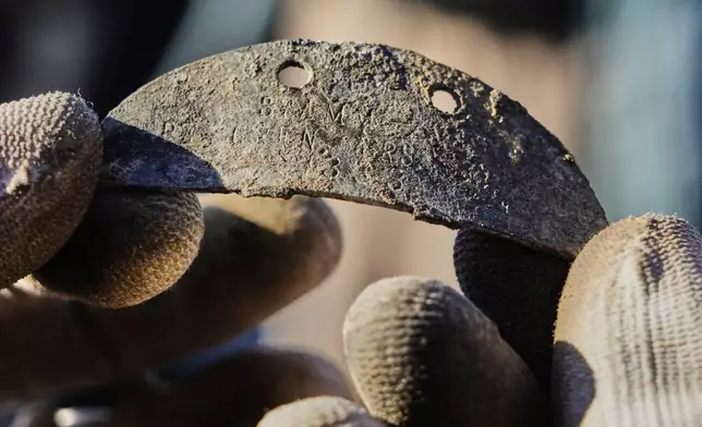 A worker of the German War Graves Commission holds a dog tag of a fallen German WWII soldier in his hands during a exhumation of remains of German WWII soldiers in Ostrołęka, Poland, Wednesday, March 19, 2025. (AP Photo/Czarek Sokolowski)