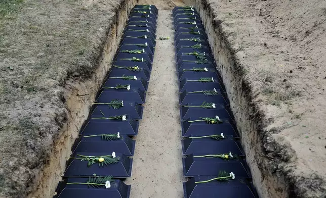 Small coffins with the remains of fallen German soldiers of WWII are placed in the mass grave during a funeral service at a memorial site for fallen soldiers in Halbe, Germany, Wednesday, April 30, 2025. (AP Photo/Ebrahim Noroozi)