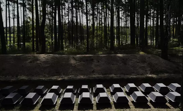 Small coffins with the remains of fallen German soldiers of WWII are placed on the ground during a funeral service at a memorial site for fallen soldiers in Halbe, Germany, Wednesday, April 30, 2025. (AP Photo/Ebrahim Noroozi)
