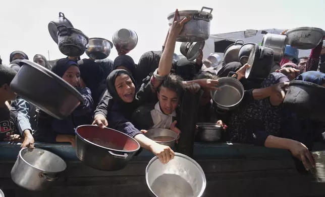 Palestinians struggle to get donated food at a community kitchen in Khan Younis, Gaza Strip, Monday, May 5, 2025. (AP Photo/Abdel Kareem Hana)