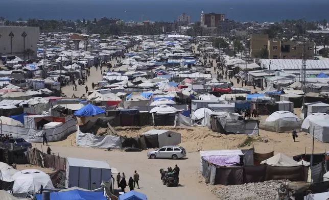 Displaced Palestinians walk through a makeshift tent camp in the Muwasi area of Khan Younis, in the Gaza Strip, on Monday, May 5, 2025. (AP Photo/Abdel Kareem Hana)