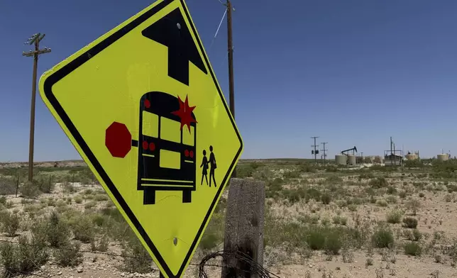 A sign warns drivers of a school bus stop near an oilfield, on the outskirts of Loving, N.M., on Tuesday, May 19, 2025. (AP Photo/Susan Montoya Bryan)
