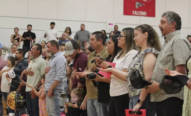 Family and friends recite the New Mexico state flag pledge ahead of a kindergartens' graduation ceremony at the elementary school in Loving, N.M., on Tuesday, May 20, 2025. (AP Photo/Susan Montoya Bryan)