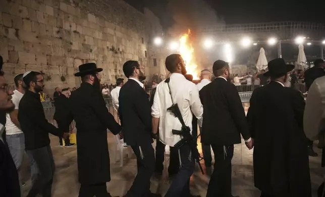 Ultra-Orthodox Jews dance around a bonfire during Lag BaOmer celebrations at the Western Wall, the holiest site where Jews can pray, in the Old City of Jerusalem, Thursday, May 15, 2025. (AP Photo/Ohad Zwigenberg)