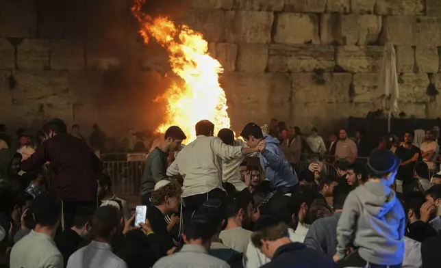 Ultra-Orthodox Jews dance around a bonfire during Lag BaOmer celebrations at the Western Wall, the holiest site where Jews can pray, in the Old City of Jerusalem, Thursday, May 15, 2025. (AP Photo/Ohad Zwigenberg)