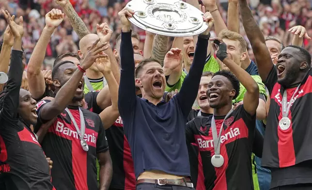 FILE - Leverkusen's head coach Xabi Alonso celebrates with the trophy as his team won the German Bundesliga, after the German Bundesliga soccer match between Bayer Leverkusen and FC Augsburg at the BayArena in Leverkusen, Germany, Saturday, May 18, 2024. (AP Photo/Martin Meissner, File)