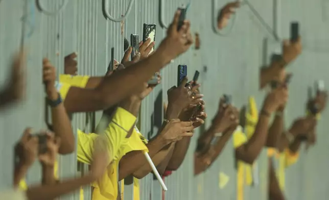 Fans stand behind a fence and use their mobile phones to take pictures of players before the start of an Indian Premier League cricket match in Chennai, India, Friday, April 25, 2025. (AP Photo/R. Parthibhan)