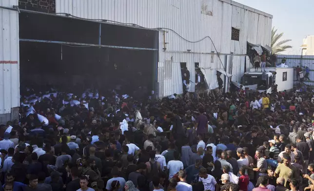 Palestinians storming a U.N. World Food Program warehouse and carry bags of flour in Zawaida, Central Gaza Strip, on Wednesday, May 28, 2025. (AP Photo/Abdel Kareem Hana)