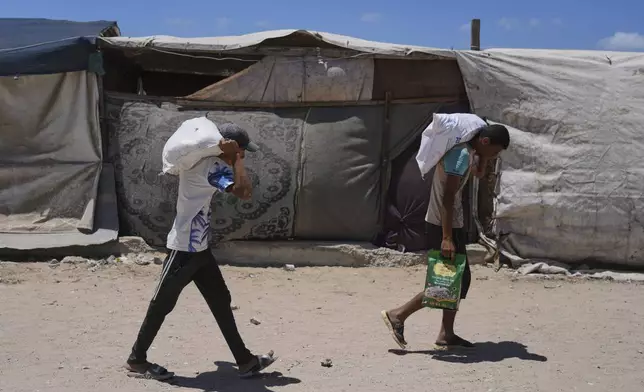 Palestinians carry food and humanitarian aid delivered by the U.S.-backed Gaza Humanitarian Foundation, after receiving the supplies in Rafah, as they arrive in Khan Younis, southern Gaza Strip, on Wednesday, May 28, 2025. (AP Photo/Abdel Kareem Hana)