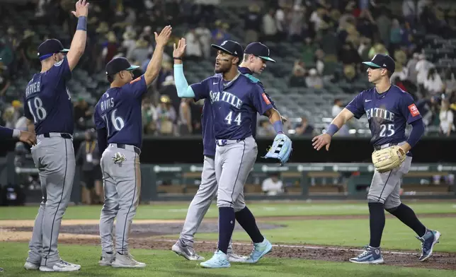 Seattle Mariners' Julio Rodríguez (44) high fives Leo Rivas (76) after their victory over the Athletics during the ninth inning of a baseball game Tuesday, May 6, 2025, in West Sacramento, Calif. (AP Photo/Scott Marshall)