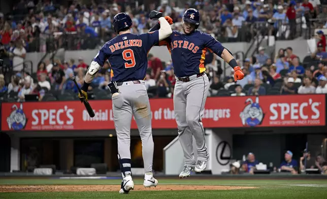 Houston Astros' Zach Dezenzo, left, and teammate Yainer Diaz, right, celebrate after Diaz hit a home run off Texas Rangers starting pitcher Jack Leiter during the seventh inning of a baseball game in Arlington, Texas, Sunday, May 18, 2025. (AP Photo/Jerome Miron)