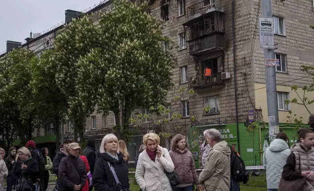 A municipal worker clear the rubble from a balcony of a residential building damaged after a Russian strike in Kyiv, Ukraine, on Wednesday, May 7, 2025. (AP Photo/Evgeniy Maloletka)
