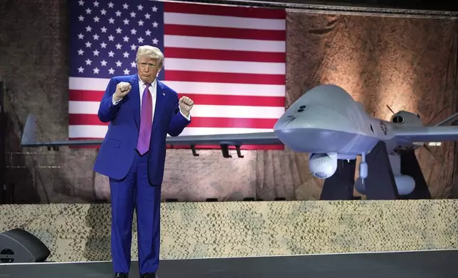 President Donald Trump gestures backdropped by an MQ-9 Reaper drone at the Al Udeid Air Base, Thursday, May 15, 2025, in Doha, Qatar. (AP Photo/Alex Brandon)