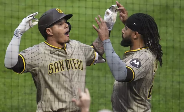 San Diego Padres' Manny Machado, left, celebrates with Fernando Tatis Jr. as he returns to the dugout after hitting a solo home run off Pittsburgh Pirates pitcher Bailey Falter during the seventh inning of a baseball game in Pittsburgh, Saturday, May 3, 2025. (AP Photo/Gene J. Puskar)