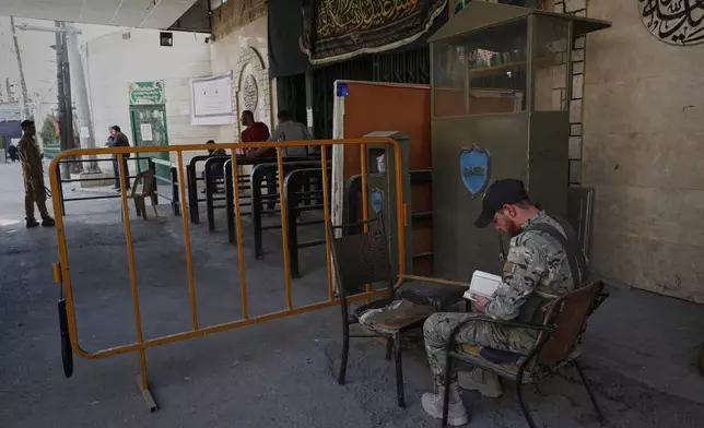 A soldier from the Syrian government army reads the Quran, the Muslim holy book, at a checkpoint near the Sayyida Zeinab Shrine, where many Shiite Muslims believe Zeinab, the granddaughter of the Prophet Muhammad, is buried, in Sayyida Zeinab, south of Damascus, Syria, Saturday, March 15, 2025. (AP Photo/Omar Sanadiki)