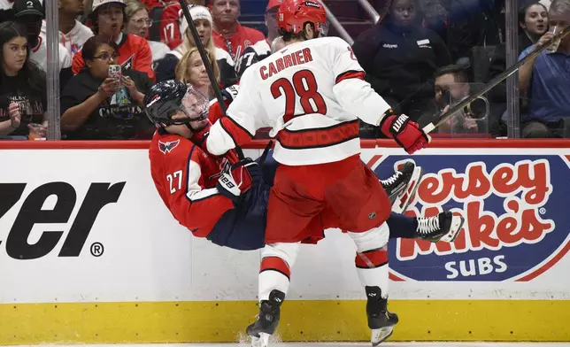Carolina Hurricanes left wing William Carrier (28) collides with Washington Capitals defenseman Alexander Alexeyev (27) in the second period of Game 1 of a second-round NHL hockey playoff series Tuesday, May 6, 2025, in Washington. (AP Photo/Nick Wass)