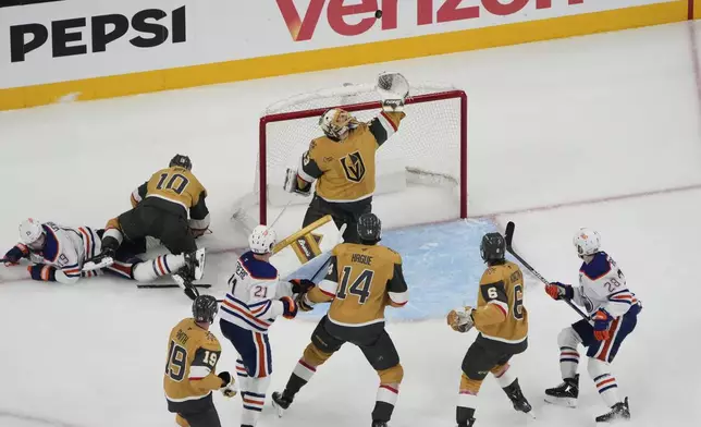 Vegas Golden Knights goaltender Adin Hill (33) reaches for the puck during the second period of Game 1 of a second-round NHL hockey playoff series against the Edmonton Oilers, Tuesday, May 6, 2025, in Las Vegas. (AP Photo/John Locher)