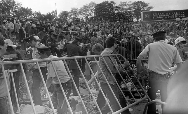 FILE - Belgian policemen and volunteers clear the scene after a disastrous clash between rival soccer fans at the European Cup Final at Heysel Stadium in Brussels, Belgium, on May 29, 1985. (AP Photo, File)