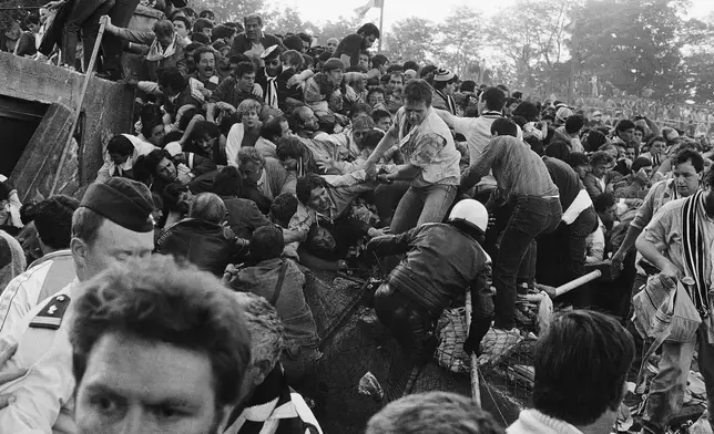 FILE - A crowd of soccer fans in the Brussels Heysel stadium, falls down in a heavy group over the broken fence just prior to the European Champion's Cup Final between Liverpool and Juventus of Turin, in Brussels, Belgium, May 29, 1985. (AP Photo/Gianni Foggia, File)