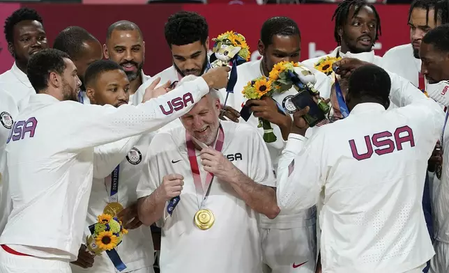 FILE - United States players put a gold medal on head coach Gregg Popovich during the men's basketball medal ceremony at the 2020 Summer Olympics, Saturday, Aug. 7, 2021, in Tokyo, Japan. (AP Photo/Charlie Neibergall, File)