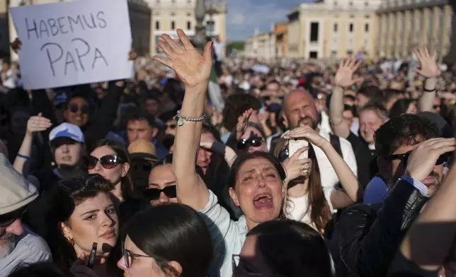 Faithful celebrate after white smoke appeared from the chimney of the Sistine Chapel where 133 cardinals gathered on the second day of the conclave to elect a successor to late Pope Francis, at the Vatican, Thursday, May 8, 2025. (AP Photo/Emilio Morenatti)