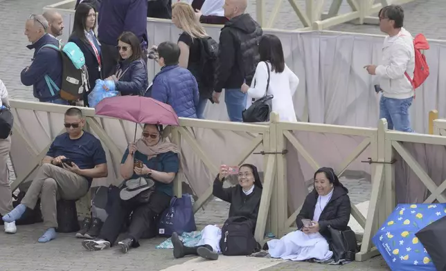 People arrive at St. Peter's Square at the Vatican where 133 cardinals gather on the second day of the conclave to elect successor of late Pope Francis, Thursday, May 8, 2025. (AP Photo/Markus Schreiber)