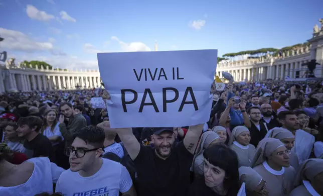 Faithful hold a banner reading "Up with the pope", after white smoke billows from the chimney of the Sistine Chapel during the conclave to elect a new pope, at the Vatican, Thursday, May 8, 2025. (AP Photo/Andrew Medichini)