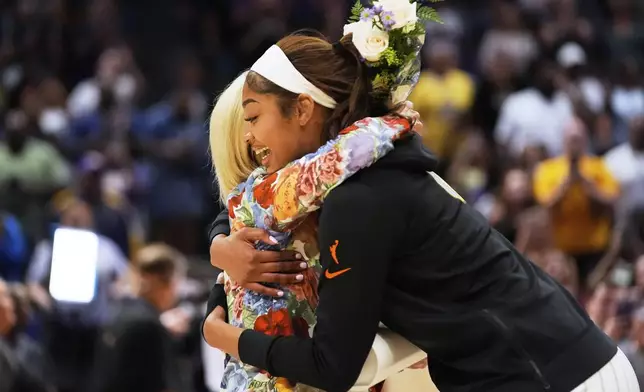 Chicago Sky forward Angel Reese hugs her former coach, LSU's Kim Mulkey, as she presents Reese flowers before a WNBA exhibition basketball game against Brazil in Baton Rouge, La., Friday, May 2, 2025. (AP Photo/Gerald Herbert)