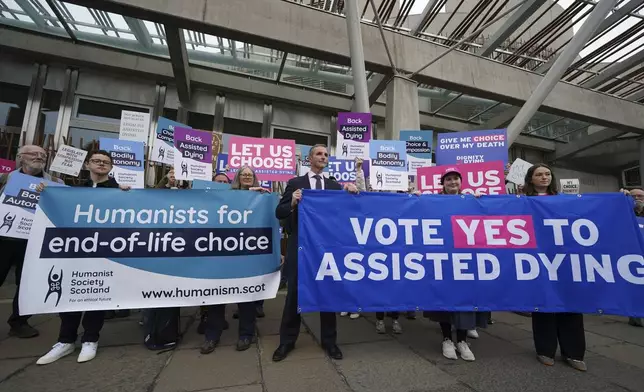 Liberal Democrat MSP Liam McArthur, centre, stands with supporters of a change in the law on assisted dying outside the Scottish Parliament in Edinburgh, ahead of the debate and vote on the Assisted Dying for Terminally Ill Adults (Scotland) Bill Tuesday, May 13, 2025. (Andrew Milligan/PA via AP)