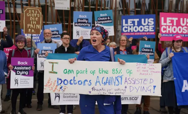 Doctor Geri Hignett protests against a change in the law on assisted dying, beside protesters demonstrating in support, outside the Scottish Parliament in Edinburgh, ahead of the debate and vote on the Assisted Dying for Terminally Ill Adults (Scotland) Bill Tuesday, May 13, 2025. (Andrew Milligan/PA via AP)