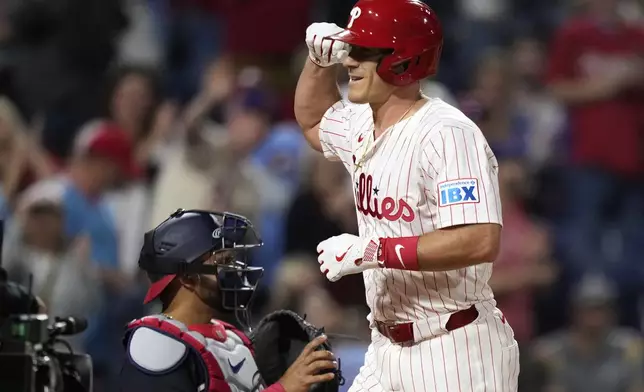 Philadelphia Phillies' J.T. Realmuto, right, reacts past Washington Nationals catcher Keibert Ruiz after hitting a home against pitcher Eduardo Salazar during the eighth inning of a baseball game, Wednesday, April 30, 2025, in Philadelphia. (AP Photo/Matt Slocum)