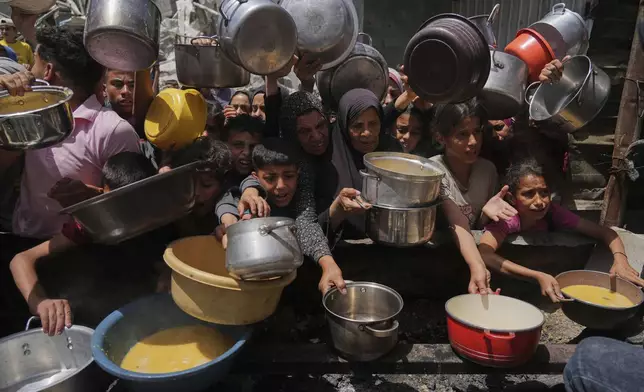 Palestinians struggle to get donated food at a community kitchen in Jabalia, northern Gaza Strip, Monday, May 19, 2025. (AP Photo/Jehad Alshrafi)