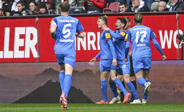 Kiel's Ivan Nekic, second left, celebrates with his teammates after scoring against Augsburg during the German Bundesliga soccer match between FC Augsburg and Holstein Kiel at the WWK-Arena in Augsburg, Germany, Sunday, May 4, 2025. (Armin Weigel/dpa via AP)