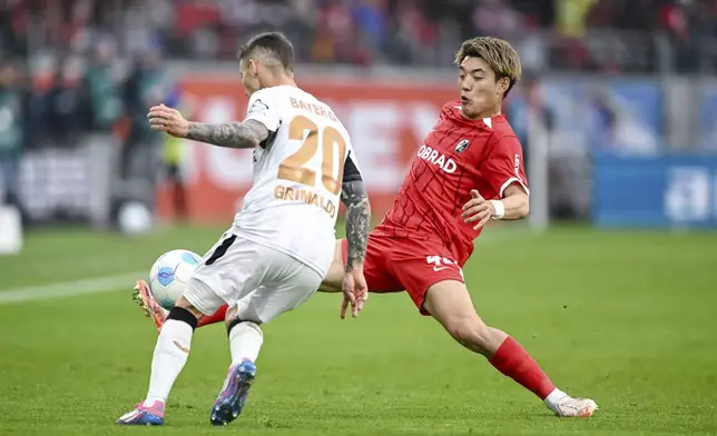 Leverkusen's Alejandro Grimaldo, left, vies for the ball with Freiburg's Ritsu Doan, during the German Bundesliga soccer match between, SC Freiburg and Bayer Leverkusen, at Europa-Park Stadium, in Freiburg im Breisgau, Germany, Sunday, May 4, 2025. (Harry Langer/dpa via AP)