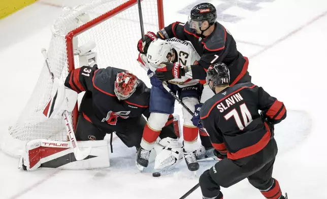 Florida Panthers center Carter Verhaeghe (23) battles Carolina Hurricanes goaltender Frederik Andersen (31), defenseman Dmitry Orlov (7) and defenseman Jaccob Slavin (74) during the second period of Game 5 of the NHL hockey Stanley Cup Eastern Conference finals Wednesday, May 28, 2025, in Raleigh, N.C. (AP Photo/Chris Seward)