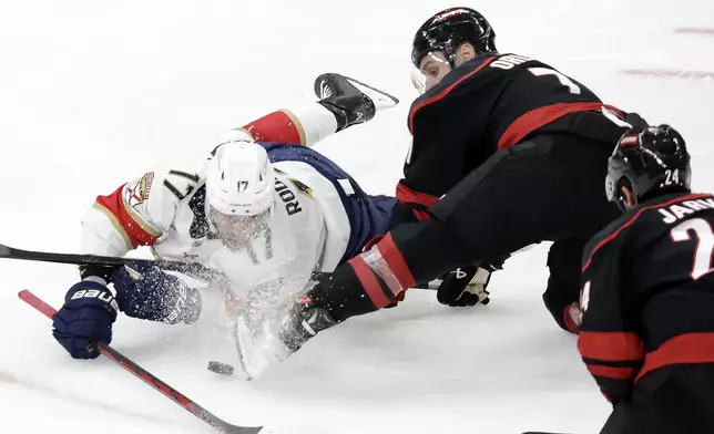 Florida Panthers center Evan Rodrigues (17) and Carolina Hurricanes defenseman Dmitry Orlov (7) battle for the puck during the third period of Game 5 of the NHL hockey Stanley Cup Eastern Conference finals Wednesday, May 28, 2025, in Raleigh, N.C. (AP Photo/Chris Seward)