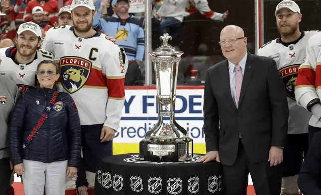 Florida Panthers center Aleksander Barkov (C) and NHL Deputy Commissioner Bill Daly, right, pose with the Prince of Wales trophy at the end of Game 5 of the NHL hockey Stanley Cup Eastern Conference finals Wednesday, May 28, 2025, in Raleigh, N.C. They advance to the Stanley Cup finals. (AP Photo/Chris Seward)