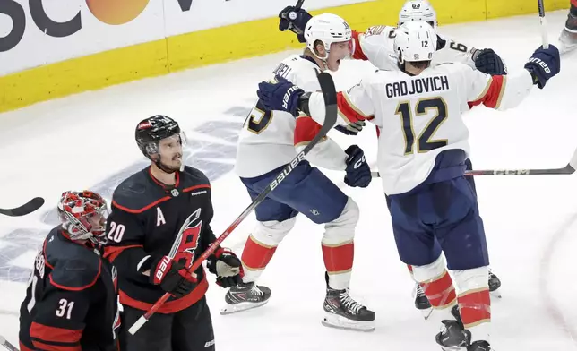 Florida Panthers center Anton Lundell (15) celebrates his goal with center Brad Marchand, top right, and left wing Jonah Gadjovich (12) while Carolina Hurricanes goaltender Frederik Andersen (31) and center Sebastian Aho (20) react during the second period in Game 5 of the NHL hockey Stanley Cup Eastern Conference finals Wednesday, May 28, 2025, in Raleigh, N.C. (AP Photo/Chris Seward)