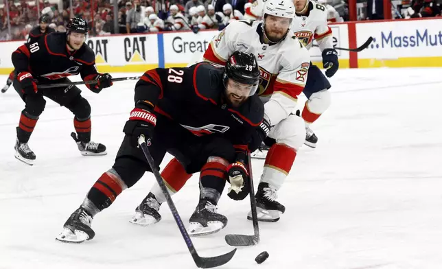 Carolina Hurricanes' William Carrier (28) battles with Florida Panthers' Dmitry Kulikov (7) for the puck during the second period of Game 5 of the NHL hockey Stanley Cup Eastern Conference finals in Raleigh, N.C., Wednesday, May 28, 2025. (AP Photo/Karl DeBlaker)