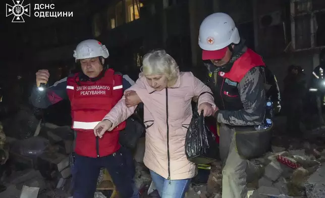 In this photo provided by the Ukrainian Emergency Service, rescuers help evacuate an elderly resident from her damaged house following Russia's air raid in Odesa, Ukraine, Thursday, May 1, 2025. (Ukrainian Emergency Service via AP)