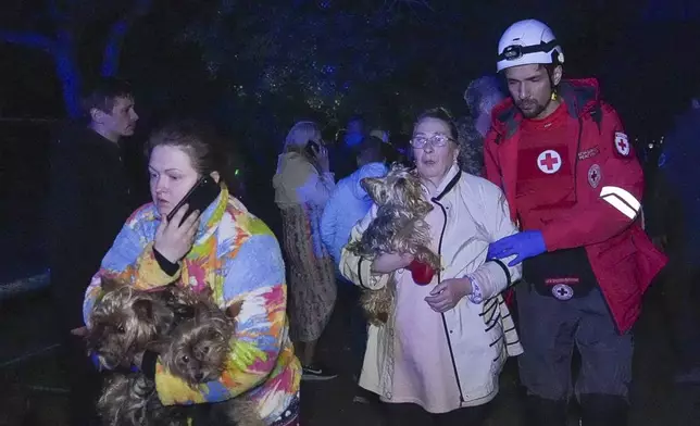 In this photo provided by the Ukrainian Emergency Service, a rescuer helps evacuate residents from their damaged house following Russia's air raid in Odesa, Ukraine, Thursday, May 1, 2025. (Ukrainian Emergency Service via AP)