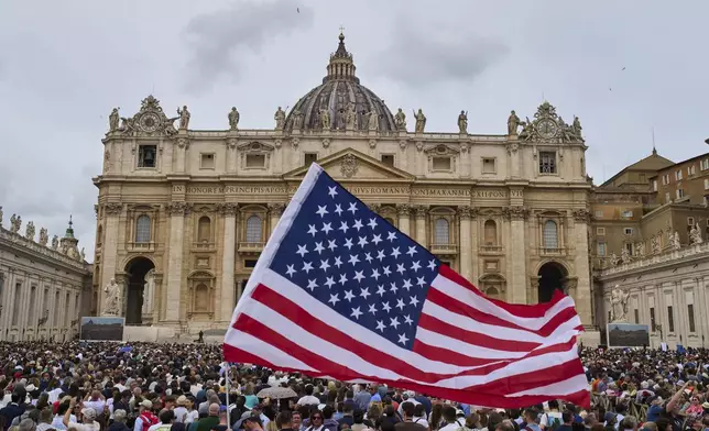 A flag from the United States waves in the crowd as Pope Leo XIV appears at the central balcony of St. Peter's Basilica for his first Sunday blessing after his election, in St. Peter's Square at the Vatican, Sunday, May 11, 2025.(AP Photo/Bernat Armangue)