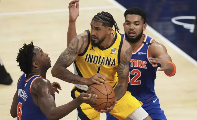Indiana Pacers forward Obi Toppin (1) looks to pass the ball between New York Knicks forward OG Anunoby, left, and center Karl-Anthony Towns during the second half of Game 3 of the Eastern Conference finals of the NBA basketball playoffs Sunday, May 25, 2025, in Indianapolis. (AP Photo/Jeff Roberson)