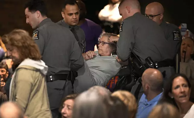 A woman is carried out by law enforcement at a town hall held by U.S. Rep. Mike Lawler, R-N.Y., Sunday, May 4, 2025, in Somers, N.Y. (AP Photo/Jessica Hill)