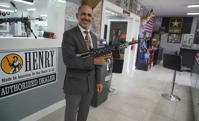 Army veteran and mayoral candidate Freddie de la Cruz poses with a semiautomatic shotgun he's raffling off at Fort Liberty Pawn &amp; Gun, Friday, May, 9, 2025. (AP Photo/Allen G. Breed)