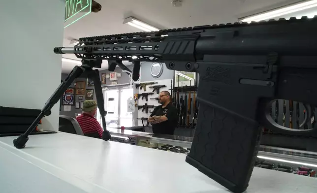 Ralph Rodriguez, right, chats with Army veteran Sidney High at his Fayetteville, N.C., pawn shop, Friday, May 9, 2025. (AP Photo/Allen G. Breed)